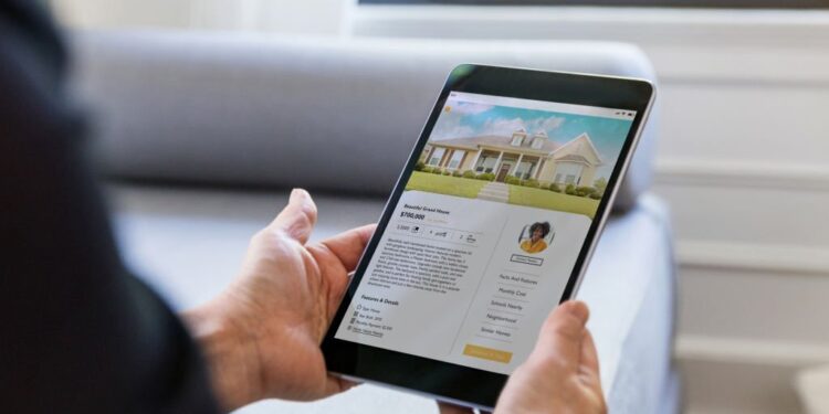 An unrecognizable man uses a real estate mobile app in his search for a new home. An exterior photo of the home is on digital tablet's screen.